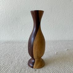 a small wooden vase sitting on top of a white tablecloth covered floor next to a wall