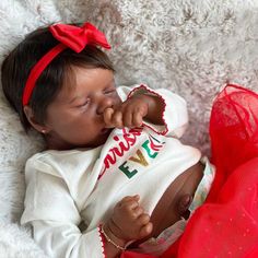 a baby doll that is laying down on a white blanket and wearing a red headband