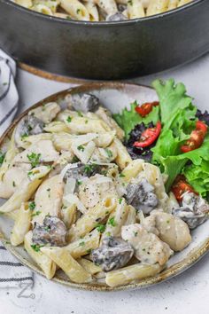 pasta with mushrooms, tomatoes and parsley on a plate next to a skillet