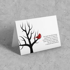 a red bird sitting on top of a tree next to a white card with a poem