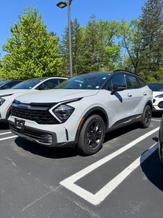 several cars parked in a parking lot with trees in the background and blue sky