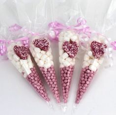 four pink and white candy sticks with hearts on them are wrapped in cellophane