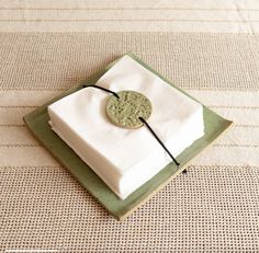 a white napkin with a green circle on it sitting on top of a square plate