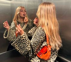 two women standing in front of an escalator and one is brushing her teeth