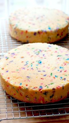 two cakes with sprinkles sitting on top of a cooling rack next to each other