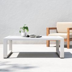 a white coffee table with a potted plant sitting on it next to a chair