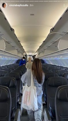 a woman is walking down an airplane aisle