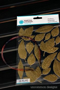 a package of gold leaf stickers sitting on top of a black table next to a pair of scissors