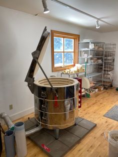 a large metal bucket sitting on top of a hard wood floor next to a window