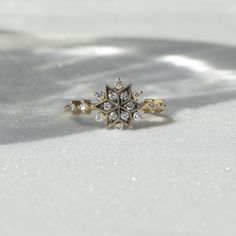 a diamond ring sitting on top of a white surface with snow flakes in the background