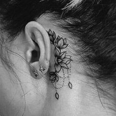 a woman's behind the ear has a flower tattoo on it