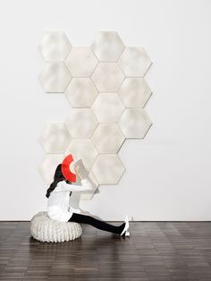 a woman sitting on the floor in front of a wall with hexagonal tiles