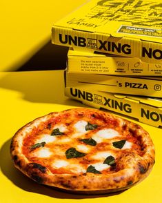 a pizza sitting on top of a yellow table next to boxes of unboxed pizza