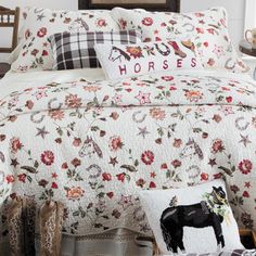 a bed covered in white and red flowers next to a wooden headboard with a black horse on it