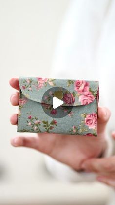 a woman holding an envelope with flowers on it and a video playing in the background