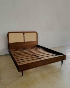 a bed with wooden headboard and foot board on concrete floor next to white wall