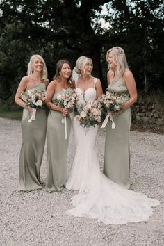 a group of women standing next to each other in front of some trees and gravel