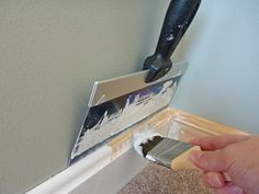 a person using a paint brush to paint the trim on a wall in their home