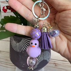 a hand holding a purple keychain with a bird on it