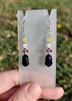 Handmade dangling earrings with black iridescent Czech glass flower beads, purple, white, and yellow crystal beads, silver-plated accent beads, and hypoallergenic silver-plated hooks. Nonbinary pride colors - lovingly handmade by a queer designer. <3 Black Iridescent, Pride Colors, Flower Beads, Dangling Earrings, Beaded Flowers, Crystal Earrings, Czech Glass, Crystal Beads, Jewelry Earrings Dangle