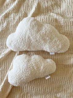 two pillows that are on top of a bed covered in white linens and one is shaped like a cloud