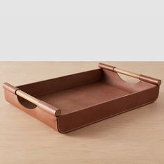 a brown leather tray sitting on top of a wooden table