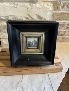 a black and white photo frame sitting on top of a wooden table