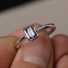 a person is holding a ring with an aquamarine colored stone in it's middle