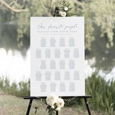 an easel with seating cards and flowers on it