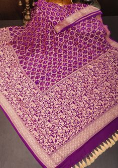 a purple and gold sari with intricate designs on the border, sitting on a table