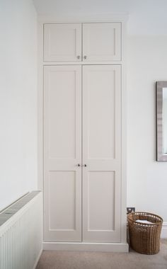 a white closet with two doors and a basket on the floor