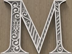 the letter m is made up of white paper with swirly designs on it's sides