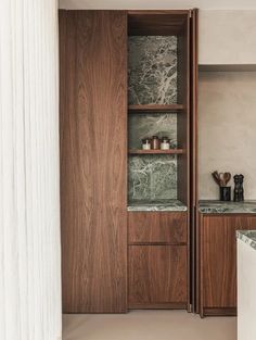 a kitchen with marble counter tops and wooden cabinetry, along with an open shelf