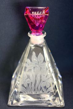 a clear glass bottle with pink and white flowers on it's top sitting on a black surface