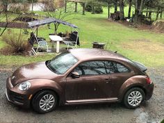 a brown car parked on top of a gravel road