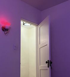 an open door leading to a bathroom with a pink light on the wall above it