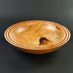 a wooden bowl with a small animal in the center on a black tablecloth background