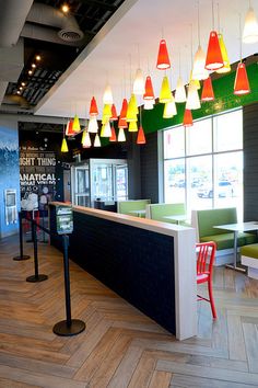 the interior of a restaurant with brightly colored lights hanging from the ceiling and chairs on the floor