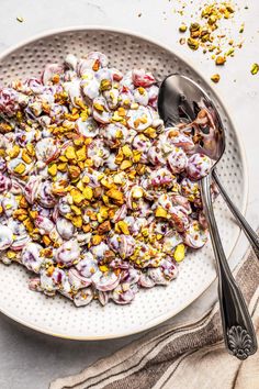 a white bowl filled with food next to two spoons on top of a table