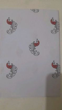 a piece of paper with red and black designs on it, sitting on a table