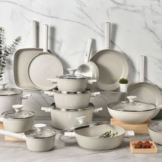 a table topped with lots of white dishes and pans