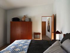 a bed sitting next to a wooden dresser in a bedroom