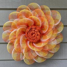 an orange and yellow mesh flower hanging on the side of a house