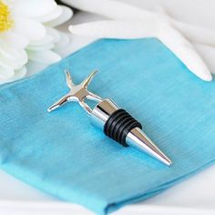 a bottle opener on top of a blue napkin next to a white and yellow flower