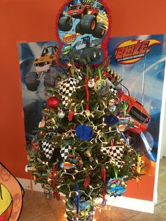 a decorated christmas tree with cars on it in front of a sign that says blaze the monster