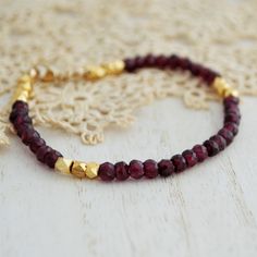 This dainty Garnet beaded bracelet features dark red faceted Garnet stones paired with 24kt gold plated copper beads. It is finished off with a gold-filled lobster clasp. The bracelet is also available in sterling silver with silver Pyrite beads instead of gold-plated ones. The beads measure 4 mm.  ----------------- FACTS ABOUT GARNET: ↦ Garnet inspires love, passion, and loyalty. ↦ It clears negativity. ↦ The birthstone for January. ↦ It is also the Wedding anniversary gemstone for the 2nd year Bohemian Gold Faceted Bracelets, Bohemian Faceted Gold Bracelets, Festive Faceted Bead Bracelets, Elegant Festive Beaded Bracelets With Faceted Beads, Adjustable Gold Ruby Bracelets, Adjustable Ruby Gold Bracelets, Gold Crystal Rondelle Bracelet With Faceted Beads, Adjustable Garnet Gold Jewelry, Gold Wedding Bracelets With Gemstone Beads