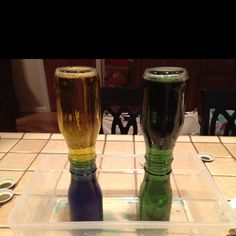 two beer glasses sitting on top of a plastic container next to each other in front of a counter