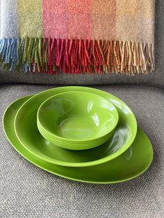 three green plates stacked on top of each other in front of a colorful throw pillow