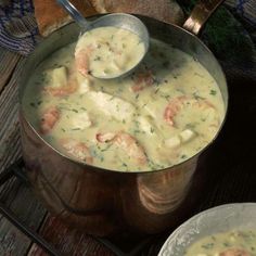 two silver pots filled with soup on top of a wooden table