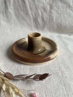 a small cup sitting on top of a saucer next to some dried flowers and leaves